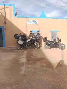een groep van drie mannen die naast motorfietsen staan bij gîte d'étape ziz oasis in Achbarou