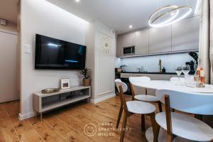 a kitchen and dining room with a white table and chairs at Happy Gold - Happy Apartamenty Mielec in Mielec