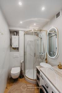 a bathroom with a shower and two sinks and a toilet at Happy Gold - Happy Apartamenty Mielec in Mielec