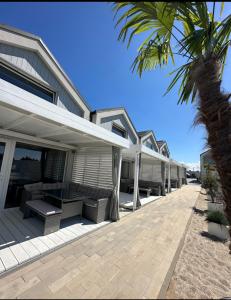 une rangée de maisons sur la plage avec un palmier dans l'établissement Silver Park, à Gąski