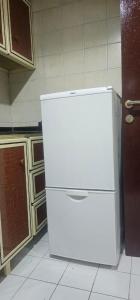 a white refrigerator freezer sitting in a kitchen at Fully Furnished Studio Appartment next to Sharaf DG metro Station in Dubai