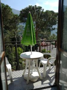 a table with a green umbrella on a balcony at Bed and Breakfast da Pio in Castelveccana