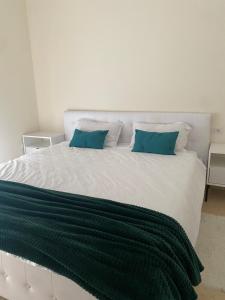 a large white bed with two blue pillows on it at Apartamente cu un dormitor in Timişoara