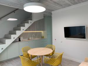 eine Küche mit einem Tisch und Stühlen sowie eine Treppe in der Unterkunft Geriausios Atostogos in Palanga