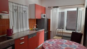 a kitchen with red cabinets and a table and a window at Family Apartment Tonko with King's Bed in Matulji