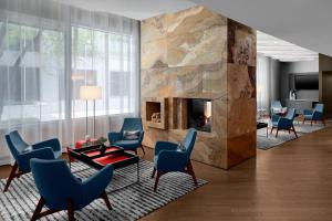 a lobby with a fireplace and blue chairs at Le Meridien Arlington in Arlington