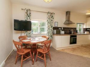 a kitchen with a wooden table with chairs and a television at The Old Dairy With Indoor Pool In Devon in Broadwoodkelly +25 photos