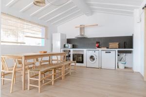 a white kitchen with a wooden table and chairs at Finca de L’ANGLÉS Casa Poniente in Potríes