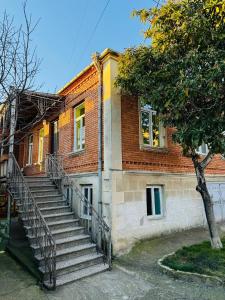 ein Backsteingebäude mit einer Treppe neben einem Baum in der Unterkunft GUEST HOUSE "BUBU" in Kutaissi