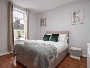 una camera bianca con un grande letto con cuscini verdi di Pass the Keys Tranquil Green Retreat - 3 Bed Tuebrook Terrace a Liverpool