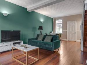 a living room with a green couch and a tv at Pass the Keys - Serene Green Retreat - 3 Bed Tuebrook Terrace in Liverpool
