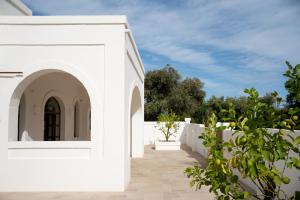 a white house with a white fence and trees at Oltre gli Ulivi in Ostuni
