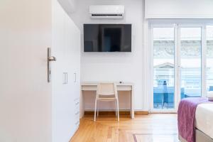 une chambre avec un bureau et une télévision au mur dans l'établissement Syntagma square, 100sqm Luxurious family apt, à Athènes