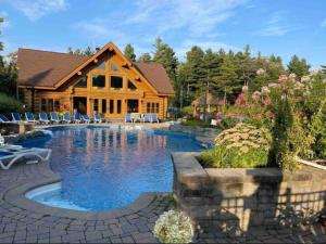 a log cabin with a pool in front of a house at Chalet Authentik 27 - Hot tub, Pools, Lake & Resort in Mille-Isles