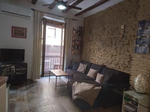 een woonkamer met een bank en een bakstenen muur bij Valencia Centro Suite in Valencia