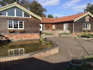 uma casa de tijolos com um lago em frente em Relaxing country cottage bungalow em Yaxley