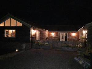 uma casa com luzes na frente à noite em Relaxing country cottage bungalow em Yaxley