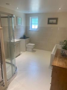uma casa de banho com um chuveiro, um WC e um lavatório. em Relaxing country cottage bungalow em Yaxley