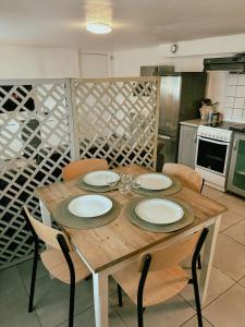 a wooden table with chairs and plates on it in a kitchen at Appartement Cosy - Proche Dysneyland - Paris - RER in Noisy-le-Grand