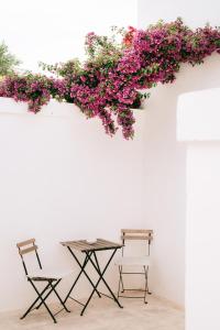 2 chaises et une table avec des fleurs sur un mur dans l'établissement Oltre gli Ulivi, à Ostuni