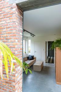 ein Wohnzimmer mit einer Backsteinwand und einer Couch in der Unterkunft stek&stoof in Sint-Pauwels