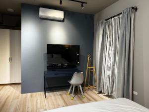 um quarto com uma cama, uma televisão e uma cadeira em 澄靛民宿 em Taitung City