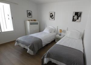a white bedroom with two beds and a window at Villa Solycan 15 in Playa del Ingles +5 photos