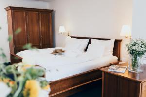 ein Schlafzimmer mit einem Bett und einer Vase aus Blumen in der Unterkunft Hotel Reindl Suiten & Appartments in Bad Füssing