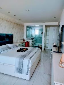 a bedroom with a large white bed and a bathroom at RICARDO Pousada - SUITE MASTER in Vila Velha