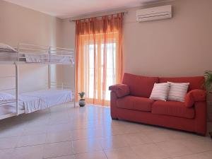 a living room with a red couch and a bunk bed at Beach House Roccalumera in Roccalumera
