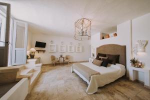 a white bedroom with a large bed and a chandelier at Masseria La Macina in Fasano