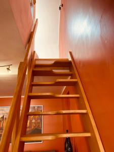 una escalera de madera en una habitación con una pared de color naranja en Studio indépendant et calme avec Jacuzzi à Lille en Lille