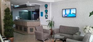 Turk Inn Uzcan Hotel في أوشاك: غرفة معيشة مع كرسيين وتلفزيون على جدار