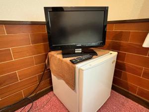 einen TV auf einem Kühlschrank in der Unterkunft ペンションパティオハウスリーフ 
