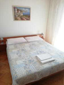 a bedroom with a bed with two white towels on it at Apartmani Ivona s pogledom na more in Podgora