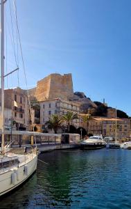 un bateau amarré dans un port de plaisance avec un château en arrière-plan dans l'établissement Résidence Confort avec Piscine - Proche des plages, à Bonifacio