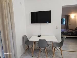 mesa blanca con sillas y TV en la pared en Guest house calme avec accès jardin et piscine, en Flayosc