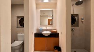 a bathroom with a sink and a toilet and a mirror at DBeds Kuta Beach By Destiny Hospitality in Kuta