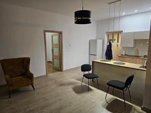 a kitchen with two stools and a counter and a chair at Apartament w Centrum Kalisza in Kalisz