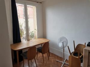 ein Esszimmer mit einem Tisch, Stühlen und einem Fenster in der Unterkunft Charmant Appartement 3 chambres - JO Paris 2024 in Colombes