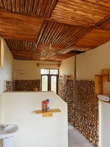 a bathroom with a sink and a wall of wood at Bwindi Neckview Lodge in Buhoma