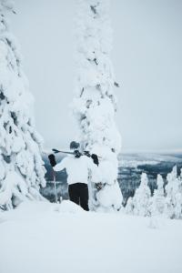 a man standing in the snow next to snow covered trees at Syöte Igloos in Syöte