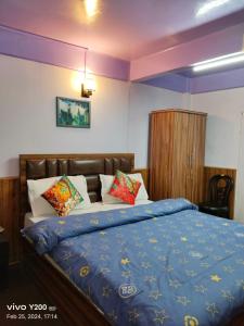 a bedroom with a large bed with a blue comforter at KDol Residency in Darjeeling