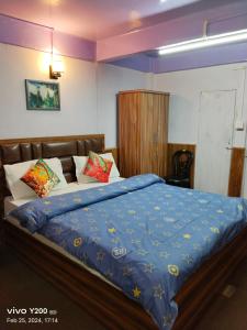 a bedroom with a large bed with a blue comforter at KDol Residency in Darjeeling