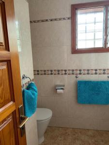 a bathroom with a toilet and a window and blue towels at Ocean View, Große Sonnenterrasse, Meerblick, Tamara Komplex, Teneriffa Süd, Los Gigantes, 500m Strand, Pool, 300m zum Ort, ruhig in Acantilado de los Gigantes