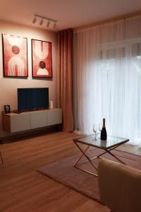 ein Wohnzimmer mit einem TV und einem Tisch in der Unterkunft Apartament Milano in Pniewy