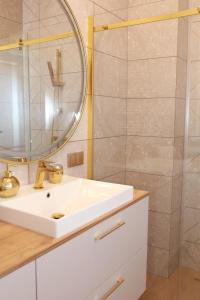 ein Bad mit einem Waschbecken, einem Spiegel und einer Dusche in der Unterkunft Apartament Milano in Pniewy