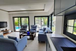 un soggiorno con divani blu e TV di Çeşme merkezde özel havuzlu villa, a Ildir