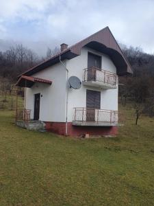 a small white house with a balcony on a field at Nikša apartment in Pljevlja