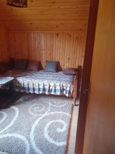 Cama en habitación con alfombra en una cabaña en Nikša apartment, en Pljevlja